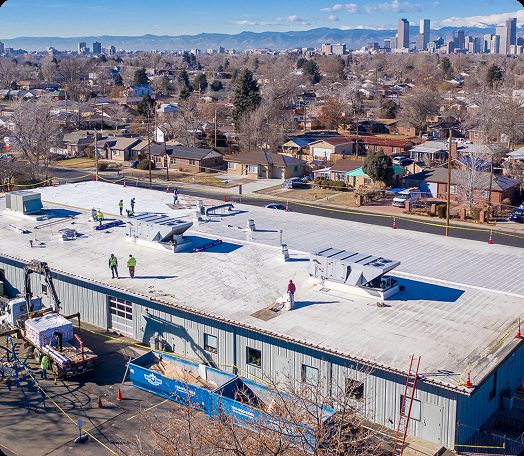 Insulation boards and roofing membrane rolls staged on a commercial flat roof in Denver