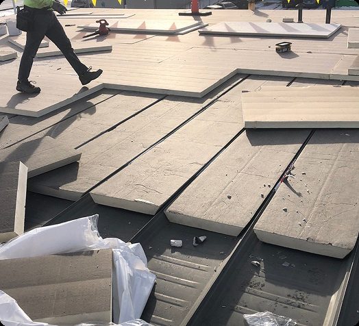 Workers installing tapered insulation boards on a commercial flat roof