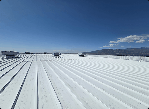 Standing seam metal roof with roof vents under a clear blue sky and mountain view
