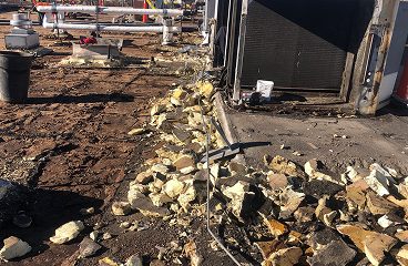 Torn-off roof insulation debris and demolition materials at a commercial roof tear-off site