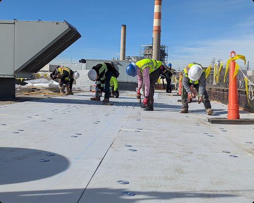 Aerial view of a completed commercial TPO roof replacement with the Denver skyline in the background