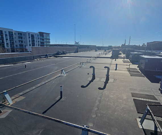 Flat commercial roof with a horizontal lifeline fall-protection system, vent pipes, and rooftop equipment