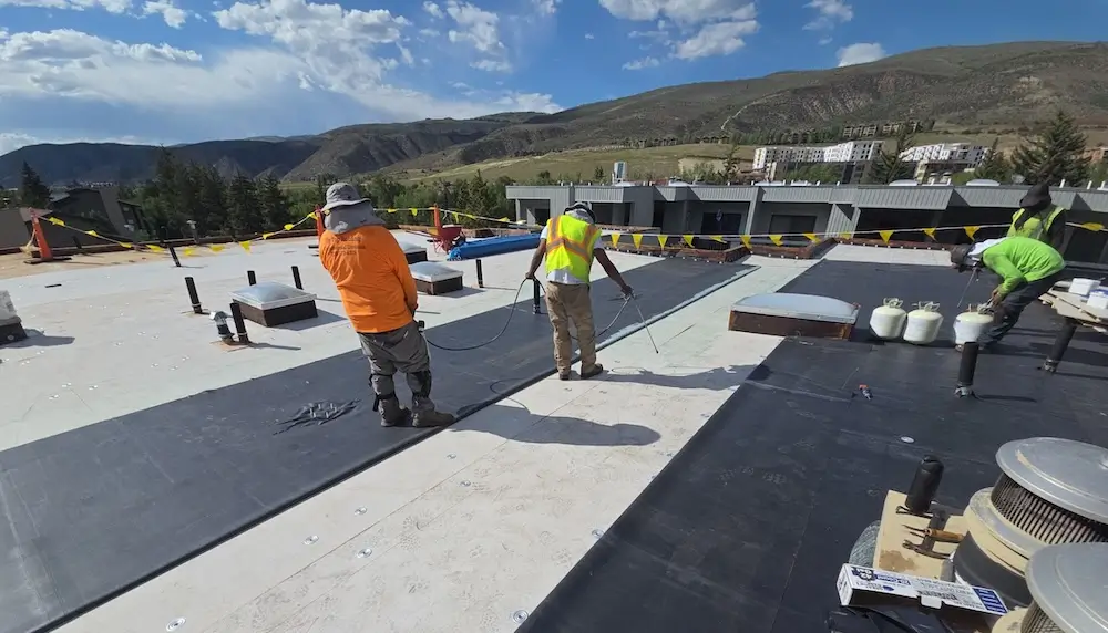 Close-up of heat-welded TPO and patched EPDM flat roofing membranes in sunlight